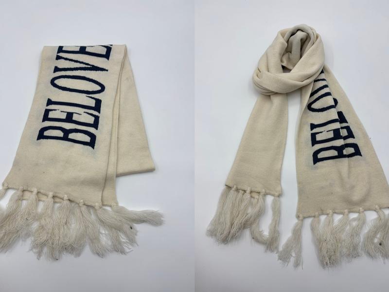 Cream knit scarf with navy blue BELOVED intarsia lettering and long fringe tassel ends, shown flat and wrapped