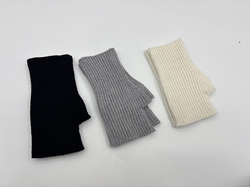 Three ribbed knit fingerless gloves laid flat in black, grey, and cream white colorways on white background