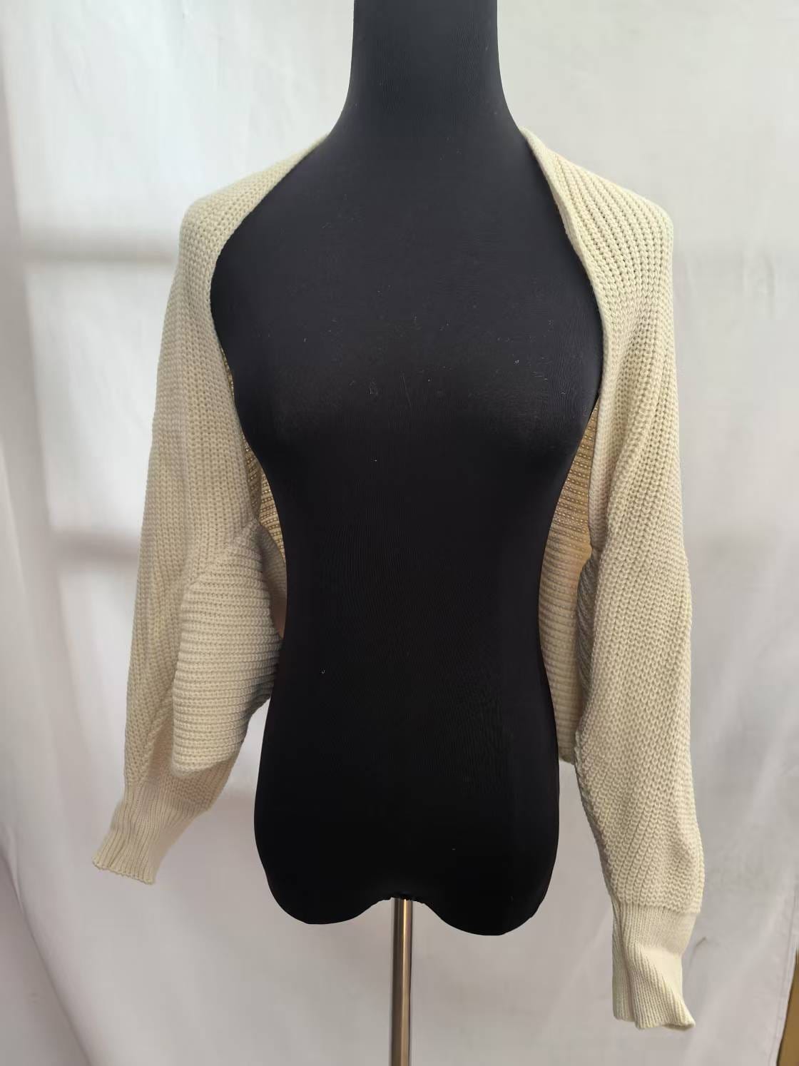 Cream chunky knit open-front bolero shrug cardigan with long sleeves and ribbed cuffs displayed on black dress form mannequin