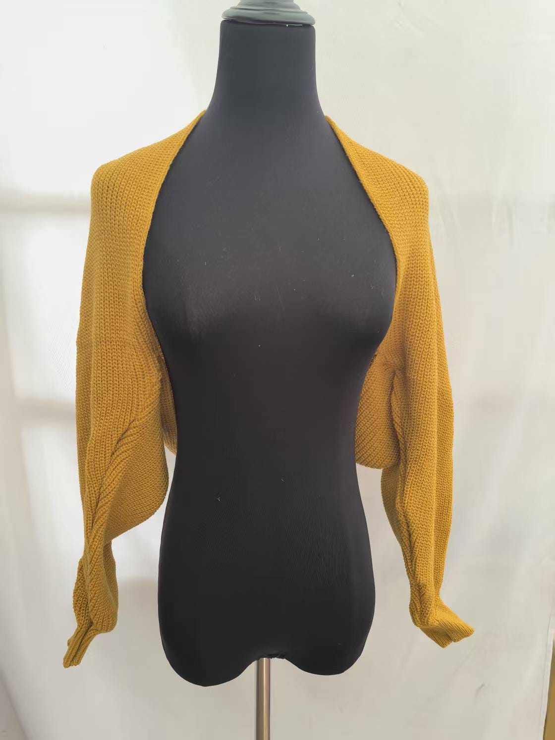 Mustard yellow chunky knit cropped bolero shrug with long sleeves displayed on a black dress form mannequin