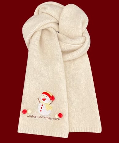Soft cream knitted scarf folded with embroidered snowman design and red pom-pom accents on dark red background