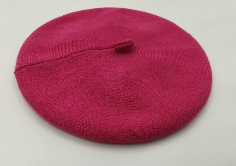 Flat lay of a hot pink fine knit wool beret with ribbed brim and center stem on white background