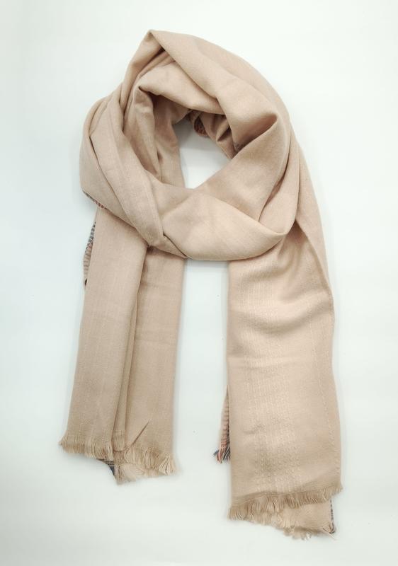 Soft beige camel-toned lightweight woven scarf loosely knotted with fringe trim ends on white background