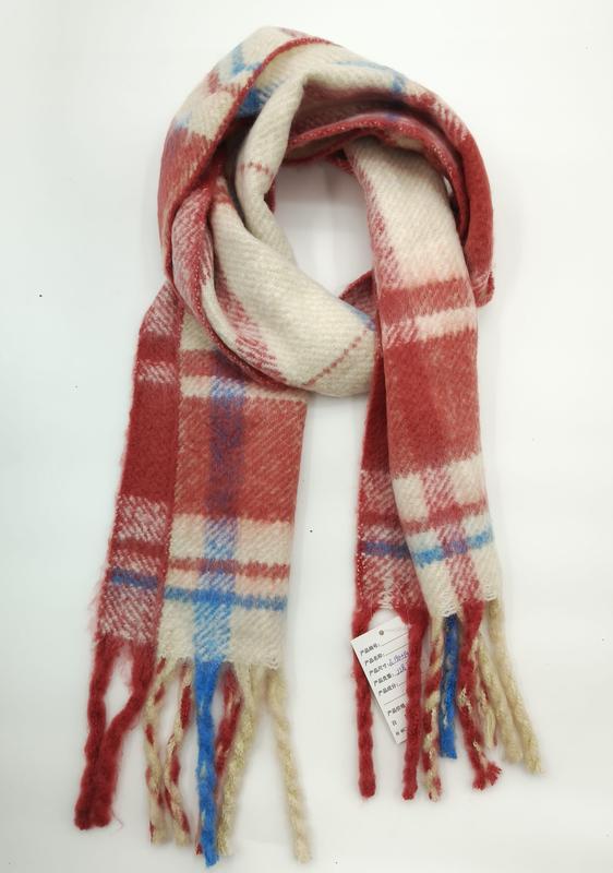 Folded red cream and blue plaid wool-blend winter scarf with multicolor fringe tassels on white background