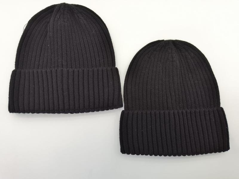 Two ribbed knit beanie hats side by side, one dark charcoal and one black, both with folded cuffs on white background