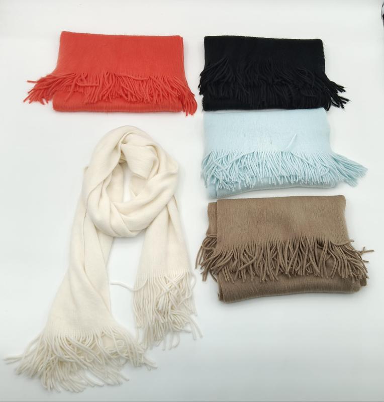 Five soft fringe scarves in cream, black, red, light blue, and tan arranged on white background, one draped open