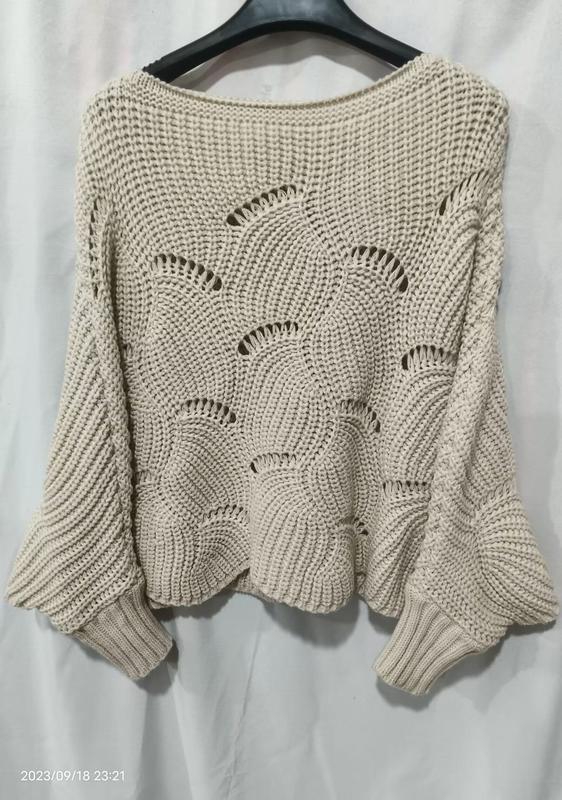 Cream beige oversized crochet knit pullover sweater with open fan stitch pattern and wide bell sleeves on hanger