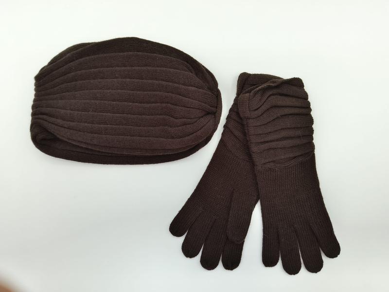 Dark brown ribbed knit winter hat and matching long gloves set laid flat on white background