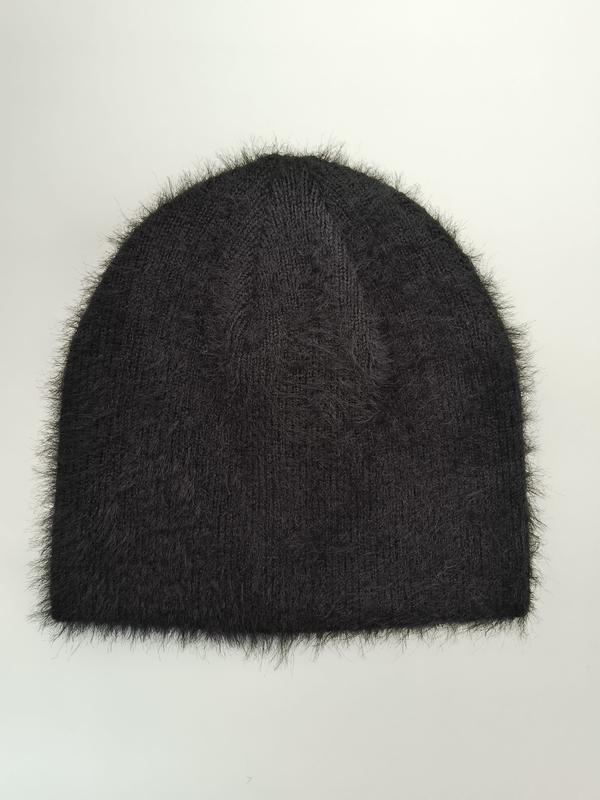 Black fuzzy knit beanie hat with fluffy mohair-style fibers and ribbed texture, laid flat on white background