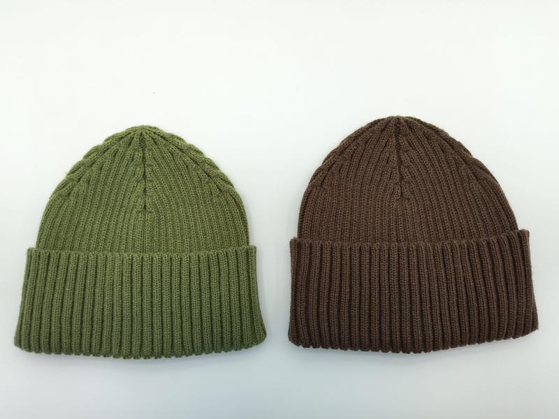 Two ribbed knit beanie hats laid flat on white background, one olive green and one brown, both with folded cuffs