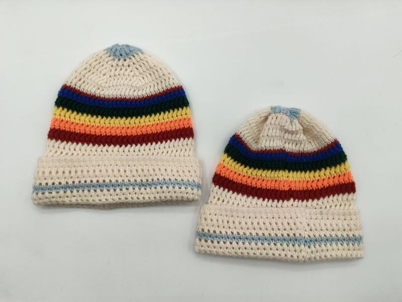 Two cream crochet beanies with rainbow stripes in blue, green, yellow, orange, red and light blue pom-top detail