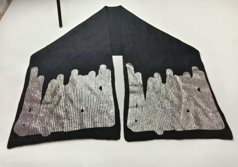 Black ribbed knit scarf laid flat showing silver metallic city skyline embroidered pattern on both ends