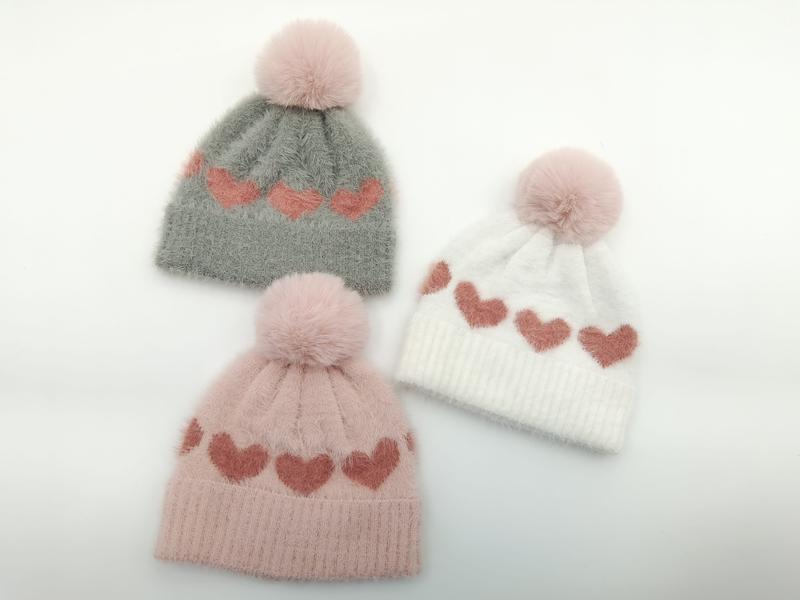 Three fuzzy knit beanies with heart pattern and faux fur pom pom in gray, pink, and white colorways