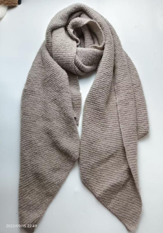 Beige taupe ribbed knit oversized scarf wrap laid flat on white surface, showing textured stripe pattern and generous length