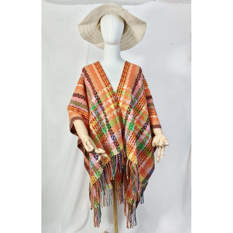 White mannequin wearing an orange multicolor geometric handwoven fringed poncho with wide-brim natural hat on white background