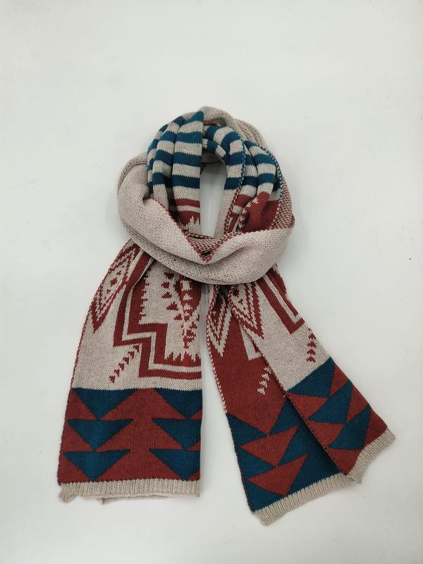Folded knit scarf with southwestern geometric pattern in cream, rust red, and teal blue on white background