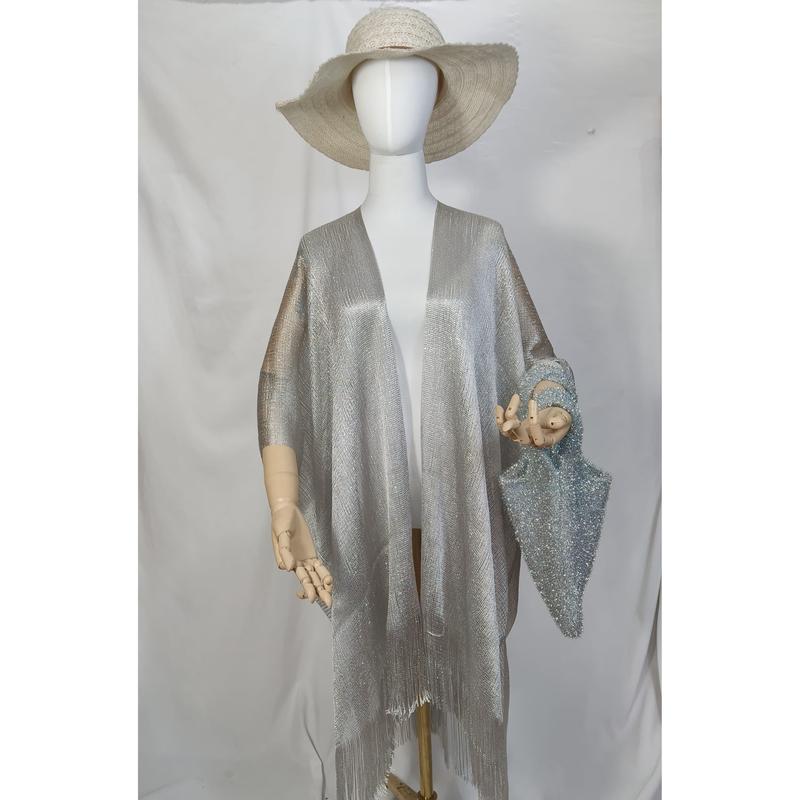 Mannequin wearing silver metallic open-front kimono wrap with fringe hem, wide-brim straw hat, and blue glitter bag