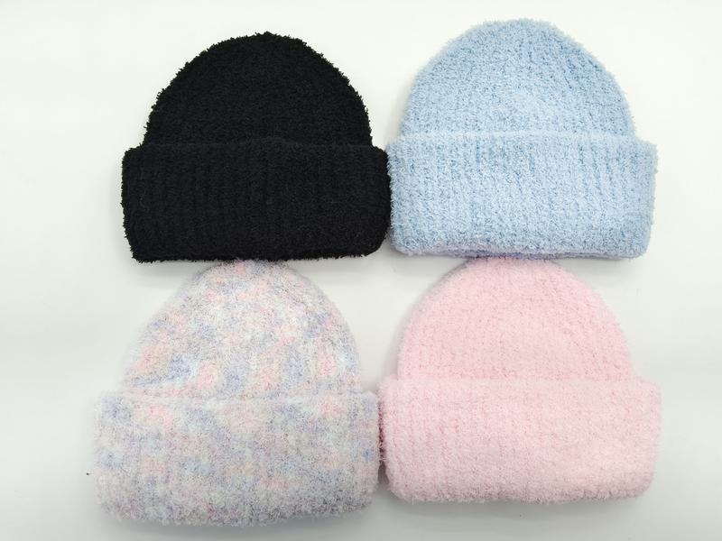 Four fuzzy knit beanies in black, light blue, pastel pink, and multicolor plaid laid flat on white background
