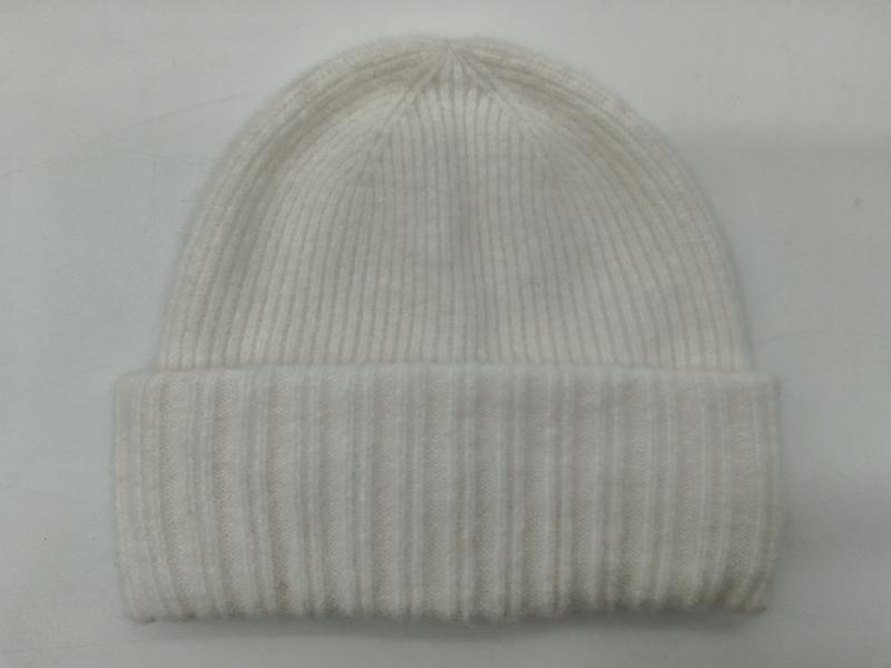 Cream white ribbed knit beanie hat with folded cuff laid flat on white background, soft wool blend winter hat