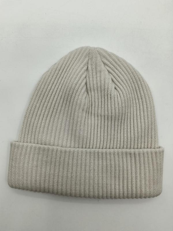 Cream ribbed knit cuffed beanie hat laid flat on white background, showing fine rib texture and folded brim