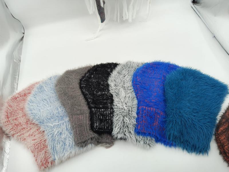 Six fluffy knit beanies in pink, blue, gray, black, white, and royal blue arranged in a fan display on white background