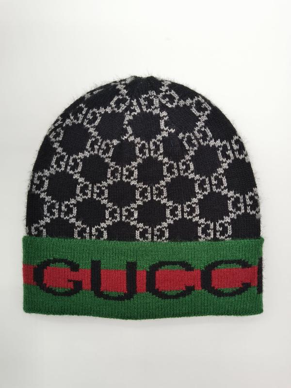 Black and grey interlocking monogram knit beanie hat with green and red striped cuff band on white background