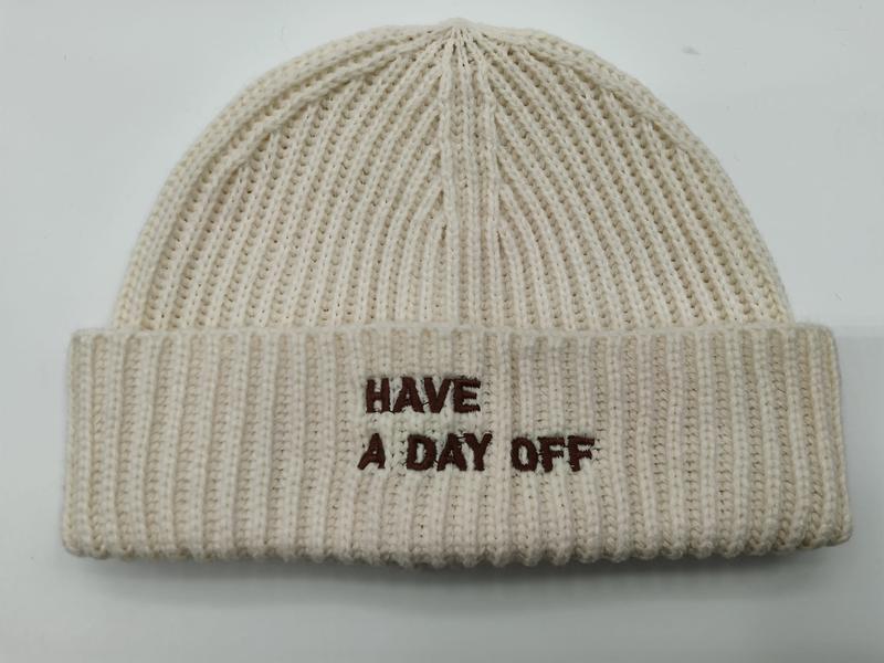 Cream chunky ribbed knit beanie hat with brown embroidered text 'Have A Day Off' on folded cuff