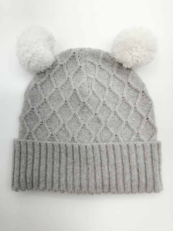 Grey cable knit winter beanie hat with two white fluffy pom poms on top, ribbed cuff, laid flat on white background