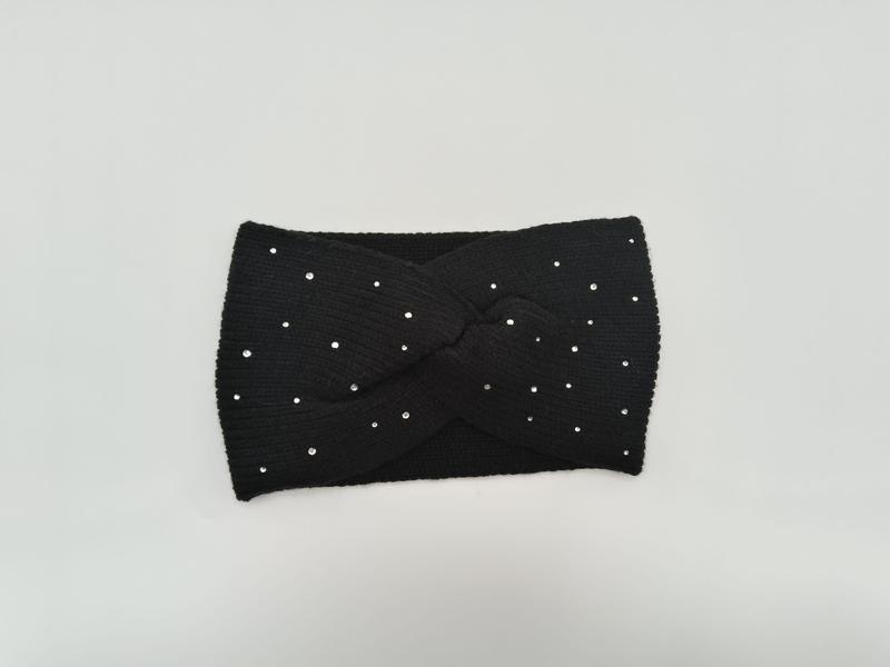 Black ribbed knit twist headband with scattered silver crystal rhinestone studs laid flat on white background