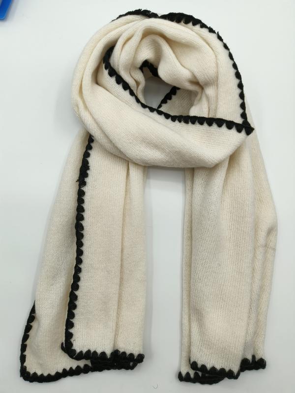 Cream ivory knitted scarf with decorative black scalloped border trim, folded and laid flat on white background