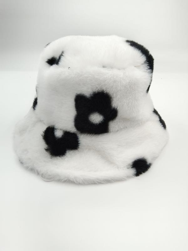 White fuzzy faux fur bucket hat featuring black daisy flower pattern, soft plush texture, displayed on white background