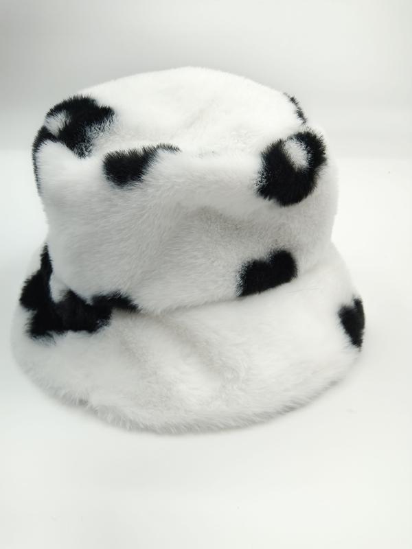 Fluffy white faux fur bucket hat with black cow spot print pattern, photographed on white background