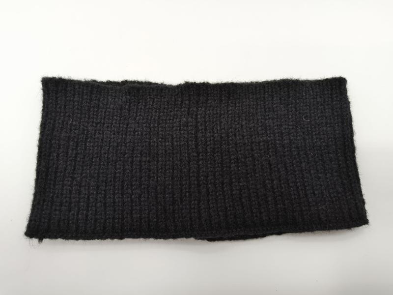Close-up of a black ribbed knit fabric swatch with vertical rib texture, shown flat on white background