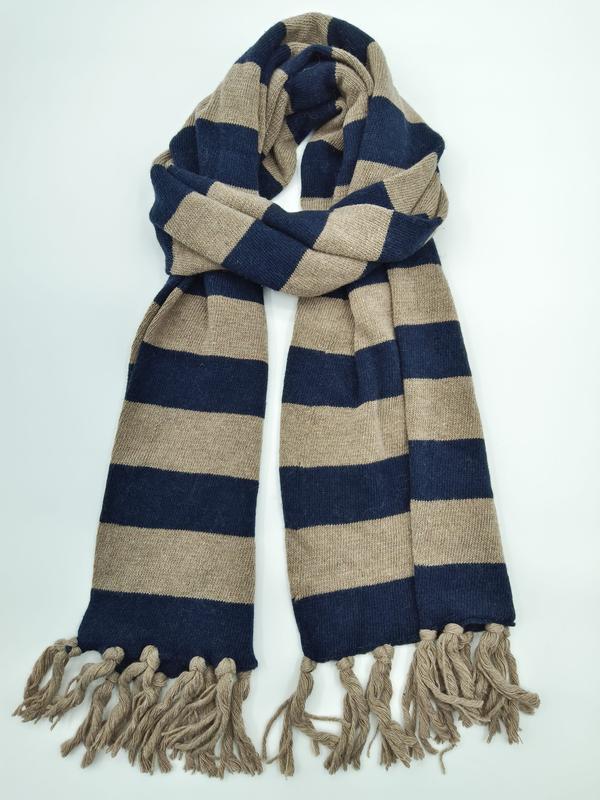 Knitted navy blue and beige wide stripe scarf with fringe tassels, loosely knotted on white background