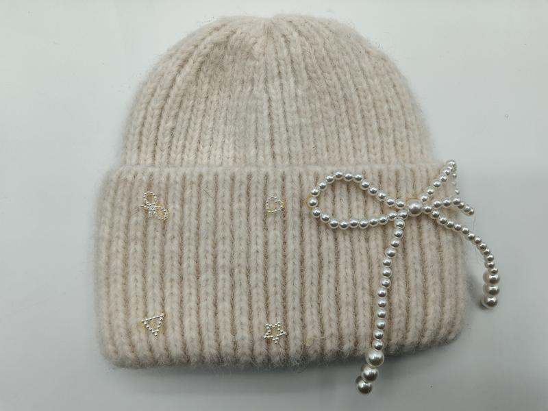 Cream ribbed knit winter beanie hat with decorative pearl bow and small rhinestone motifs on the cuff