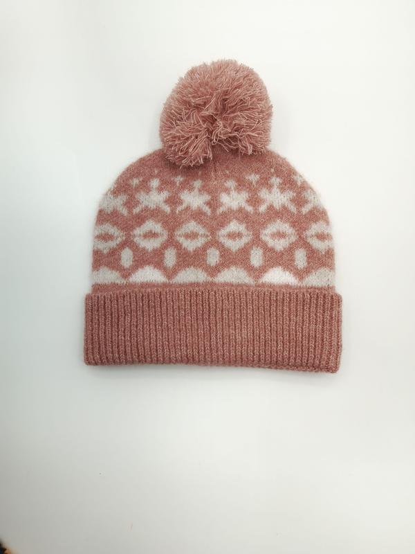 Pink and white Fair Isle knitted beanie hat with fluffy pom pom and geometric snowflake pattern on white background