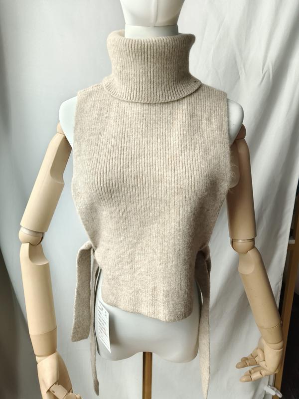 Oatmeal ribbed knit sleeveless turtleneck vest with side tie belt displayed on a mannequin, new with tags