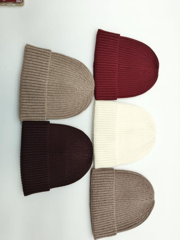Five ribbed knit beanies laid flat in beige, burgundy, cream, dark brown, and taupe on white background